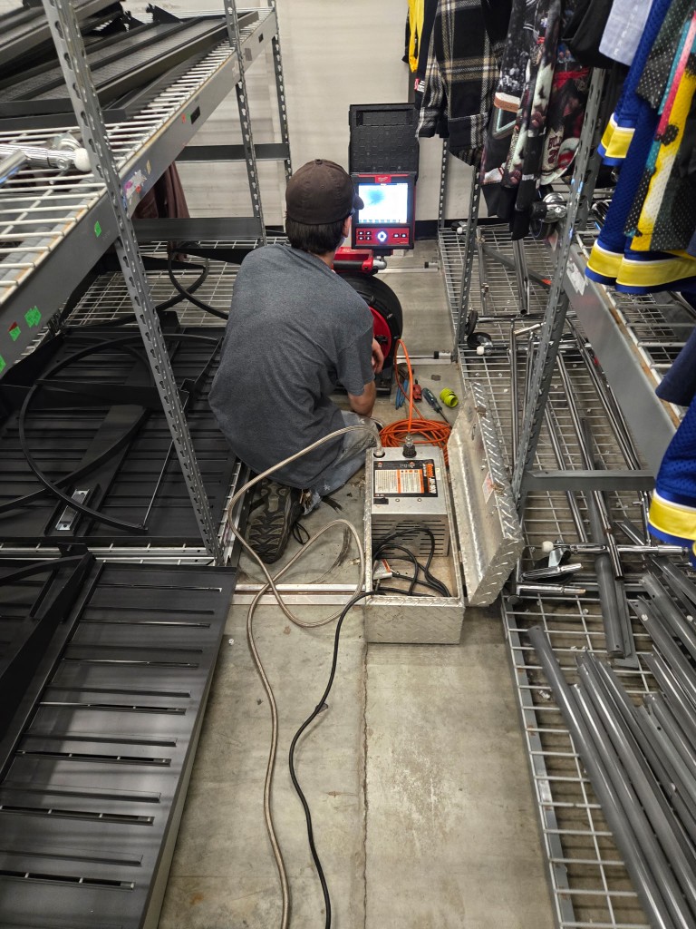 Doctor Rooter 911 technician running a sewer camera inspection in the back room of a commercial building